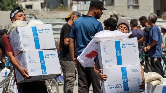 People receive humanitarian aid packages provided by the United Nations Relief and Works Agency for Palestine Refugees (UNRWA) from a warehouse in central Gaza City on August 27, 2024 amid the ongoing conflict in the Palestinian territory between Israel and Hamas. (Photo by Omar AL-QATTAA / AFP)
