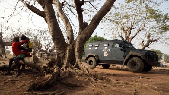 Children seen sitting a tree trunk next to an armoured personnel carrier is stationed inside the Government Science College where gunmen kidnapped dozens of students and staffs, in Kagara, Rafi Local Government Niger State, Nigeria on February 18, 2021 (Photo by Kola Sulaimon / AFP)