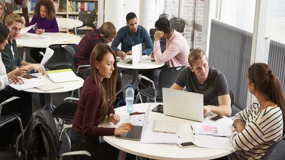 Busy University Library With Students And Tutor